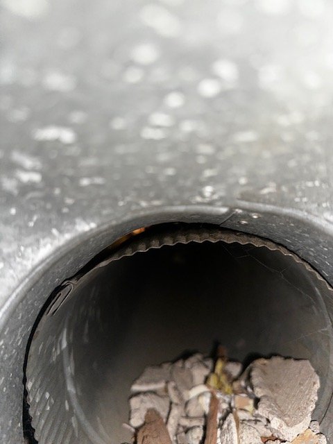Close-up view inside a duct pipe showing built-up lint and debris